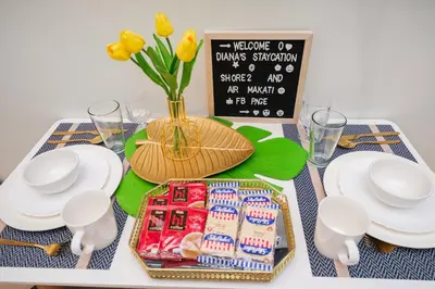 a table with a tray of food and a vase with yellow flowers at MALL OF ASIA Condo with Balcony Facing Pool @ Shore2 in Manila