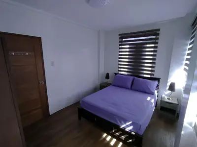 a bedroom with a bed with purple sheets and a window at Casa Maris in Bacoor