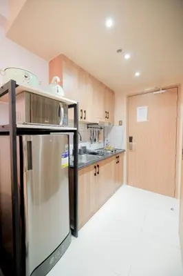 a kitchen with wooden cabinets and a stainless steel refrigerator at Shore 3 Mall of Asia - Sofian Suites in Manila