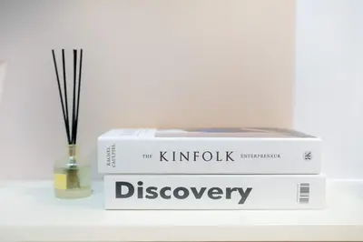 a stack of books sitting on a table with a vase at Shore 3 Mall of Asia - Sofian Suites in Manila