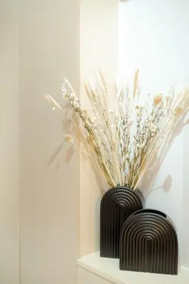 a black vase sitting on a shelf with flowers in it at Shore 3 Mall of Asia - Sofian Suites in Manila
