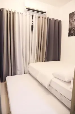 a room with gray curtains and white beds at Smdc Breeze Residence in Manila