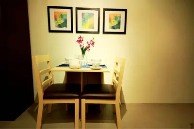 a table with two chairs and a vase with flowers on it at Fully-furnished Condo Accommodation in Makati in Manila