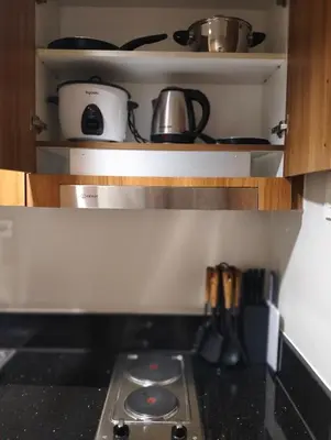 a stove top oven in a kitchen with cabinets at Cozy Condo near Mall of Asia in Manila