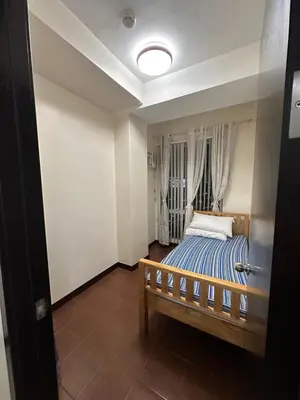 a bedroom with a bed with a blue and white striped blanket at The Ivory San Lorenzo Place Makati in Manila