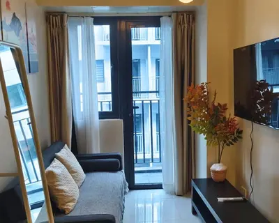 a living room with a couch and a sliding glass door at ndulge in opulence on a budget near MOA! Luxuriate in our Deluxe 1 Bedroom Units with stunning views. Enjoy free NETFLIX and an exceptional discount. Book now for a lavish and affordable escape! in Manila