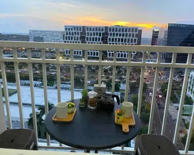 a table on a balcony with a view of a city at ndulge in opulence on a budget near MOA! Luxuriate in our Deluxe 1 Bedroom Units with stunning views. Enjoy free NETFLIX and an exceptional discount. Book now for a lavish and affordable escape! in Manila
