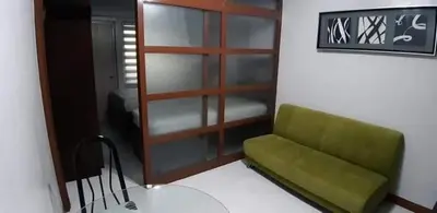 a green couch in a room with a room with a bedroom at 1BR Condo Unit W/ Fantastic View near US Embassy in Manila