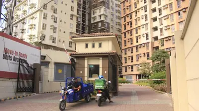 two people on motor scooters parked on a city street at Avida Sucat Tower 9 in Manila