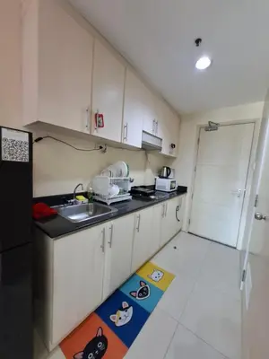 a kitchen with white cabinets and a sink and a kitchen rug at Kings staycation at mall of asia in Manila