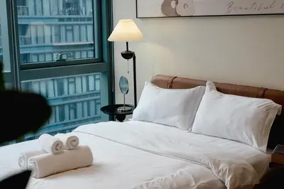 a white bed with two rolled up towels on it at Thompson Suites Queen Room, One Uptown Residences, XBOX & Netflix in Manila