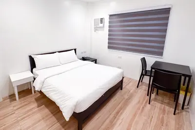 a bedroom with a bed and a table and a window at SANTOS Pension House in Manila