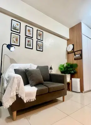 a living room with a couch and a clock on the wall at PSV NAIA T3 - Month of January - New Year 2026 PROMO Php 1,999 - 1 BR Interior Designed Unit in Manila