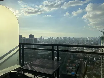 a table and chairs on a balcony with a city at Gramercy Residences 46th Floor 1 Bedroom Sunset View in Manila