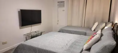 a hotel room with two beds and a flat screen tv at ADB AVENUE TOWER in Manila