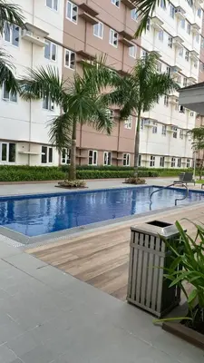 a swimming pool in front of a building with palm trees at Studio Type Condominum at SMDC HOPE Residences in Trece Martires