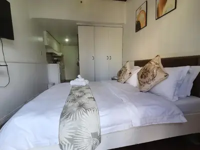 a bedroom with a large bed with white sheets and pillows at citadel inn apartment in Manila