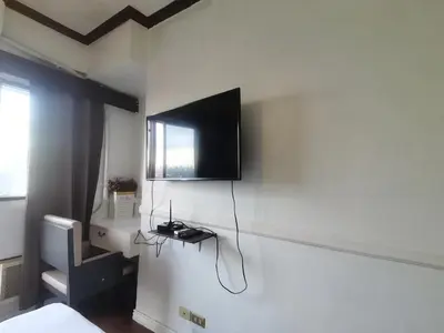 a room with a television on a wall with a bed at citadel inn apartment in Manila