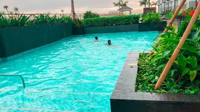 two people are swimming in a swimming pool at RQ Cozy One Bedroom Condo, Coast Residences Pasay in Manila