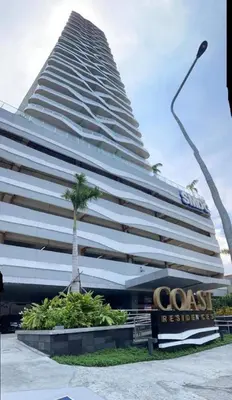 a large building with a palm tree in front of it at RQ Cozy One Bedroom Condo, Coast Residences Pasay in Manila