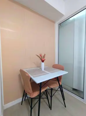 a table with two chairs and a vase of flowers on it at A3J Staycation at Azure Urban Resort Residences in Manila
