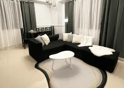 a living room with a black couch and a table at Cozy & Airy Suite near Venice Mall FREE Pool & Gym in Manila
