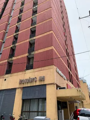 a tall red building with a sign on it at Travelers Inn - Modern Capsule Bunks, Makati in Manila