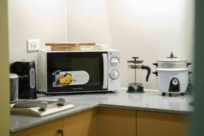 a kitchen counter with a microwave and a coffee maker at 1 BR with balcony in Uptown BGC in Manila