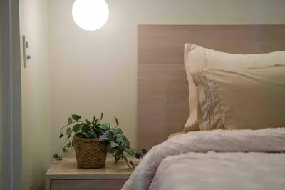 a bed with a pillow and a plant on a table at 1 BR with balcony in Uptown BGC in Manila