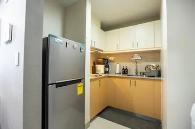 a kitchen with a stainless steel refrigerator and cabinets at Cozy 1BR with Balcony and Netflix in Uptown BGC in Manila
