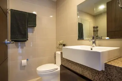 a bathroom with a white sink and a toilet at Luxury Condo at Venice Mall near Airport, BGC & Makati in Manila