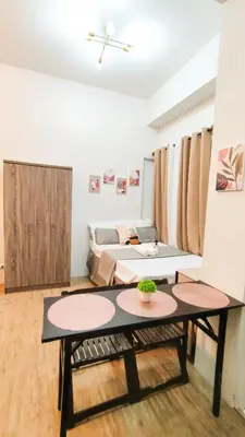 a living room with a table and a bed at Anuva Stays in Manila