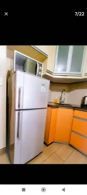 a kitchen with a white refrigerator and orange cabinets at RG condotel Near Naia Terminal 3 in Manila