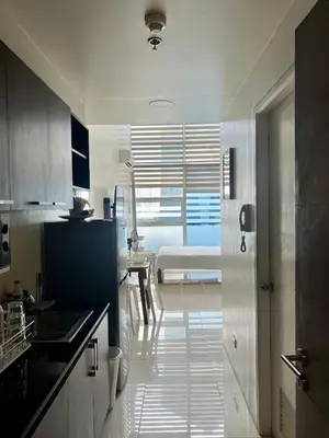 a kitchen with a sink and a room with a bed at Cozy High Ceiling Studio @ Ortigas near Podium, Megamall in Manila