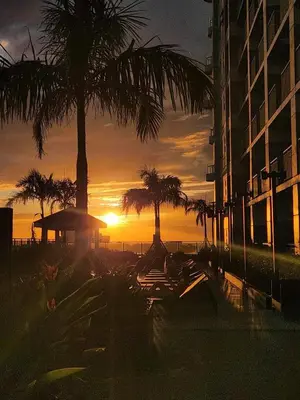 a sunset on the beach with palm trees and a building at Manila Bay Retreat at Soleil Suite in Manila