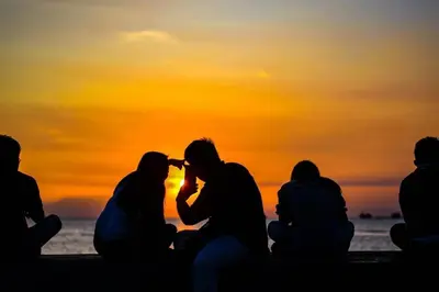 a group of people sitting on the beach watching the sunset at Shore Residence D21 shortwalk MOA Balconypoolview in Manila