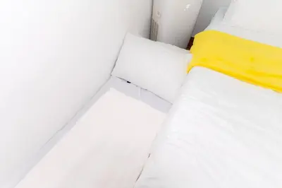 a bed with white sheets and a yellow blanket at A2J Luxury 3BR BGC Loft Near Malls and Airport in Manila
