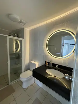 a bathroom with a sink and a toilet and a mirror at Modern Oasis: Pool + Netflix in Manila