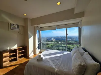 a bedroom with a large bed with a large window at The Infinity Towers in BGC - Simple, Elegant & Spacious 2 Bedroom in Manila