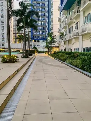 a sidewalk in a city with palm trees and buildings at Madison Place at Sea Residences powered by Cocotel in Manila