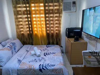 a bedroom with a bed with a tv and a couch at Pierrecondotel in Manila