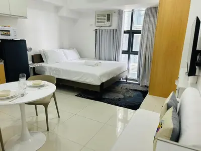 a hotel room with a bed and a table and a table and a table at 11B Tower 1 Viceroy Residences Mc Kinley Hill BGC in Manila