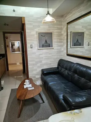 a living room with a black leather couch and a table at SHELL RESIDENCES MOA COMPLEX PASAY in Manila