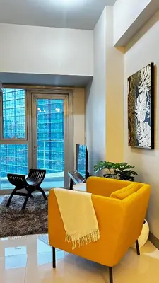 a living room with a yellow couch and a table at Uptown Parksuites Tower Two - BGC Taguig, Manila in Manila