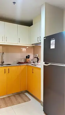 a kitchen with yellow cabinets and a black refrigerator at Uptown Parksuites Tower Two - BGC Taguig, Manila in Manila