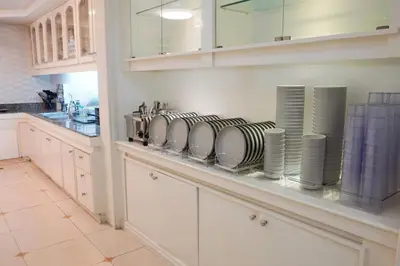 a kitchen with white cabinets and plates on a shelf at Makati Altean Apartment (Delfin Room) in Manila