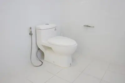 a white bathroom with a toilet with a hose at Makati Altean Apartment (Delfin Room) in Manila