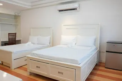 two beds in a room with white walls and wood floors at Makati Altean Apartment (Leonora Room) in Manila