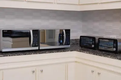 three microwaves on a counter in a kitchen at Makati Altean Apartment (Leonora Room) in Manila