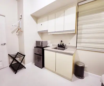 a small kitchen with white cabinets and a sink at KL Tower Condo, Makati City in Manila